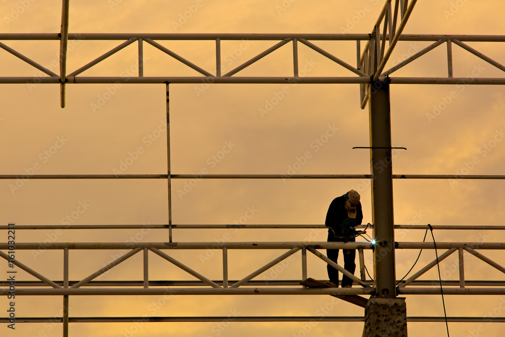 Worker welding metal at sunset