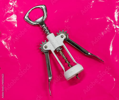 A white cork screw on a pink background.