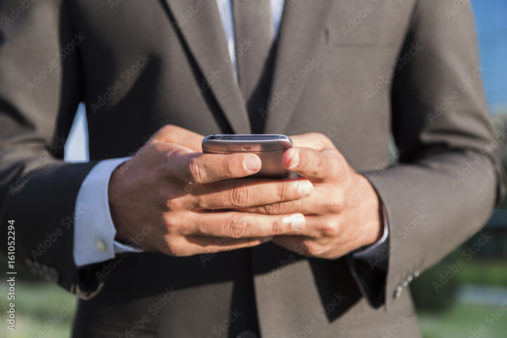 Businessman or worker standing in suit with cellphone in hands Businessman or worker standing in suit with cellphone in hands