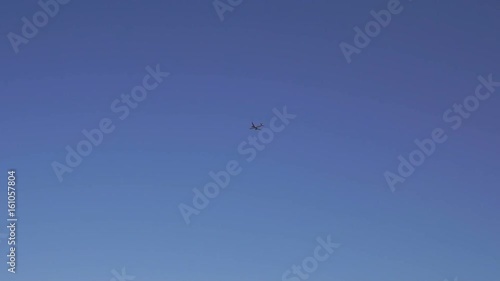 Large passenger jet flying high in clear blue sky. Beautiful view of white plane flying in blue sky. Wide shot. photo
