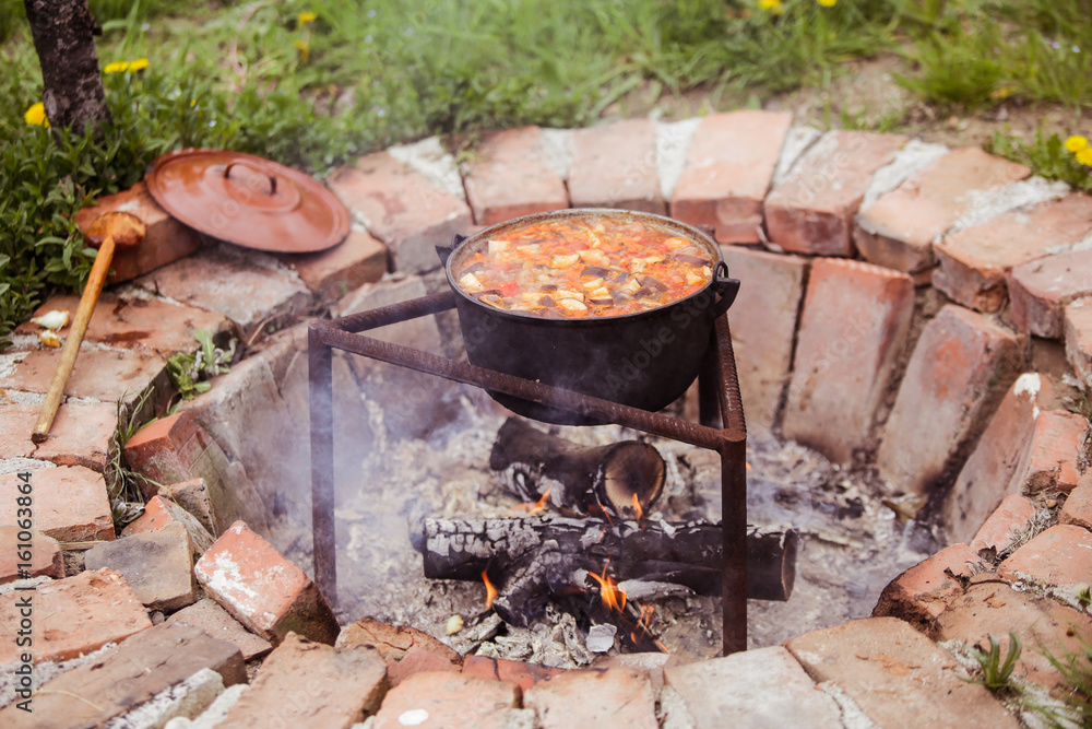 Slow cooking stew on wooden fire Slow cooking stew on wooden fire