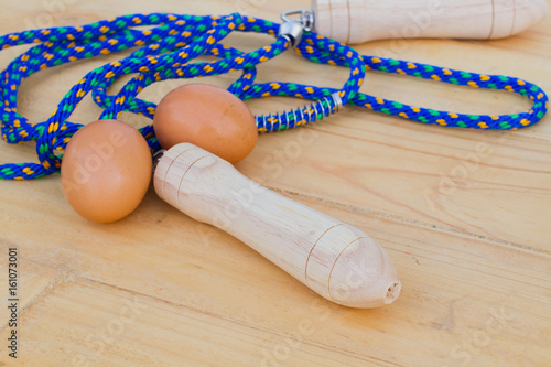 blue jump rope with two eggs on wooden bakcground. Exercising and healthy food make good sex