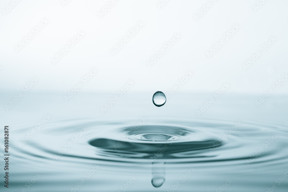 Water drop and splash on water surface on blue background