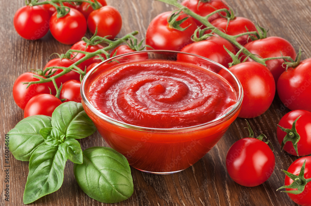 Bowl with ketchup basil and tomatoes on a wooden background. Bowl with ketchup basil and tomatoes on a wooden background.