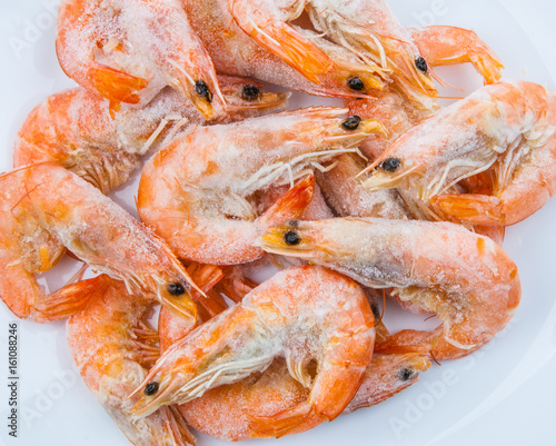 Frozen shrimp with ice cubes on a wood background