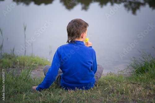 The teenager sits on the lake shore. photo