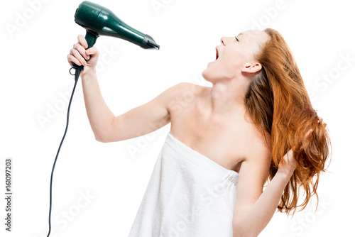 Red-haired woman dries hair with a hairdryer on a white background
