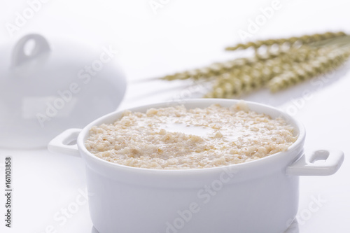 Oat porridge in a white saucepan. Oatmeal. Cap.