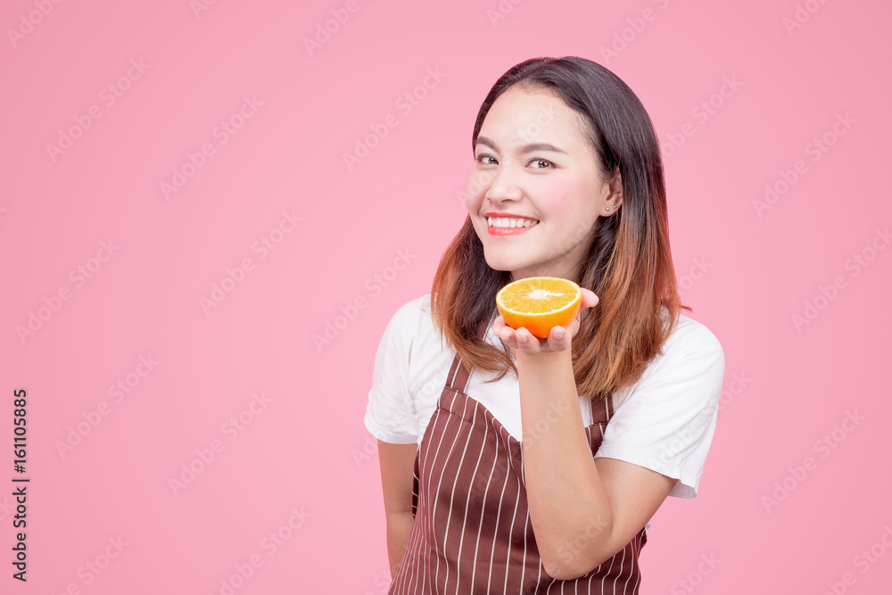 Young healthy Asian woman holds an orange in her hand on a pink background Young healthy Asian woman holds an orange in her hand on a pink background