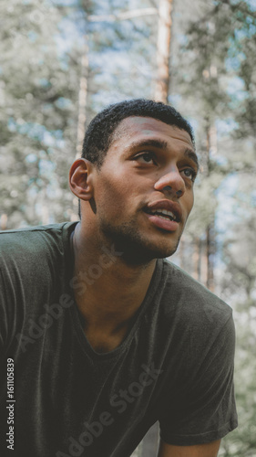 African American man preparing for a jog on a forest road. Young athletic male exercising outdoors