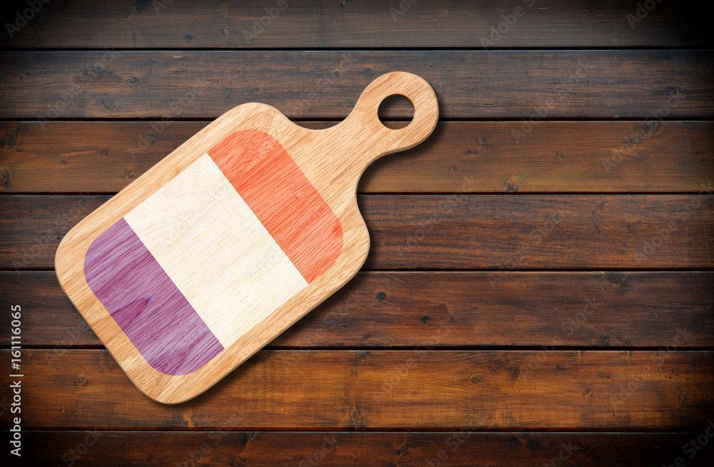 Concept of French cuisine. Cutting board with a France flag on a wooden background