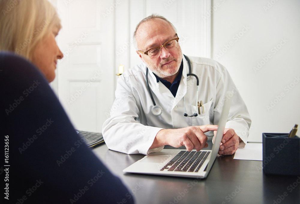 Woman listening to adult doctor explaining diagnosis with laptop