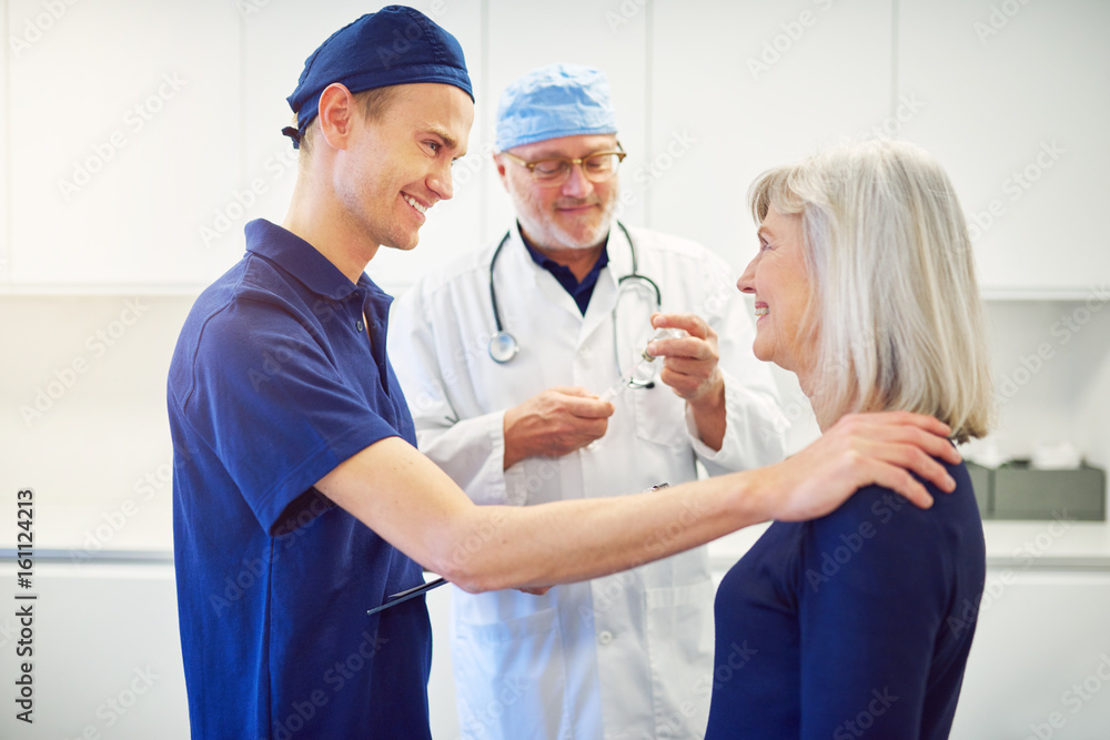 Fototapeta premium Young doctor cheering adult female patient in clinic