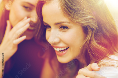 smiling young women gossiping and whispering photo