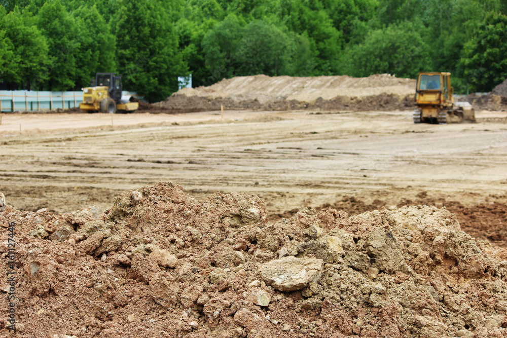 tractor and compactor are leveling and compacting the surface of the earth. Construction of the city stadium. tractor and compactor are leveling and compacting the surface of the earth. Construction of the city stadium.