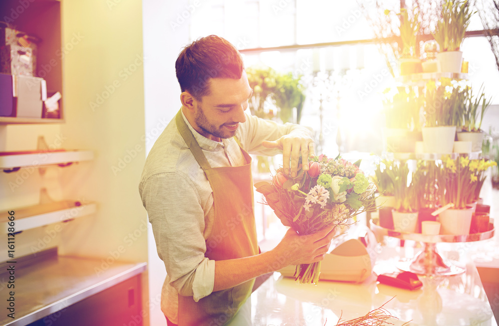 Fototapeta premium smiling florist man making bunch at flower shop