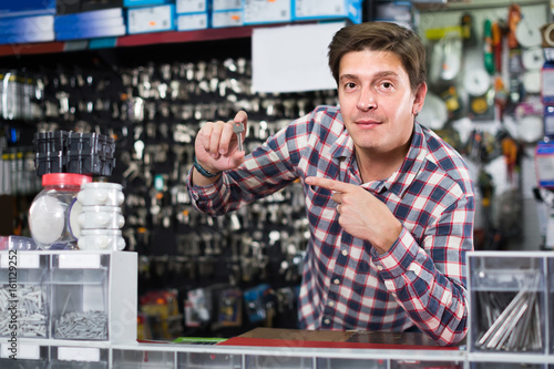 worker in hardware store trading goods and keys in uniform