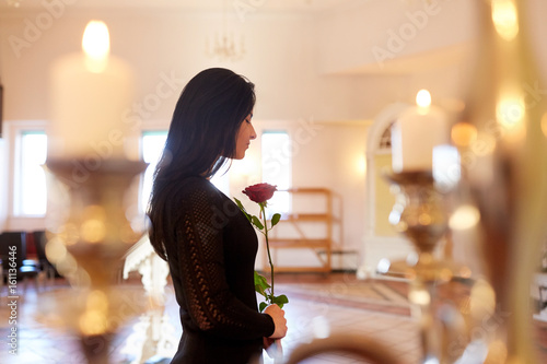 Фотография sad woman with red rose at funeral in church