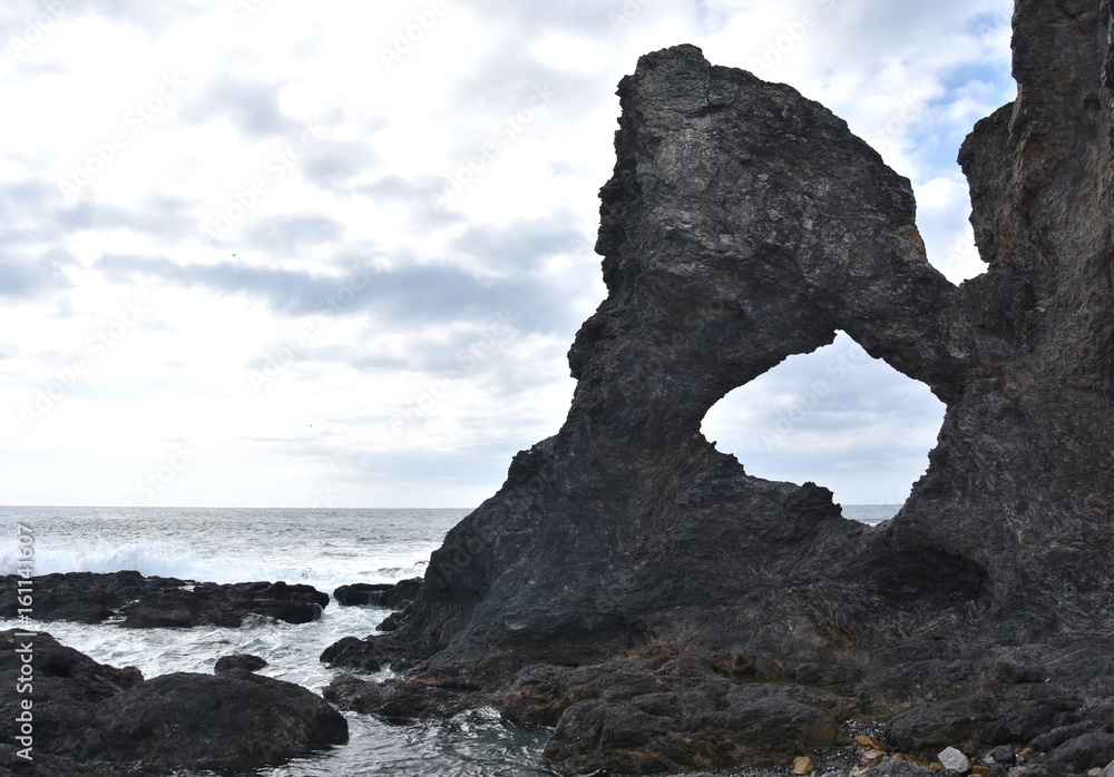 Australia rock and ocean in Narooma. The shape of Australia cut into the rock wall was accidental and was created when a ship was tied to the rock with large chains to prevent it from washing away.