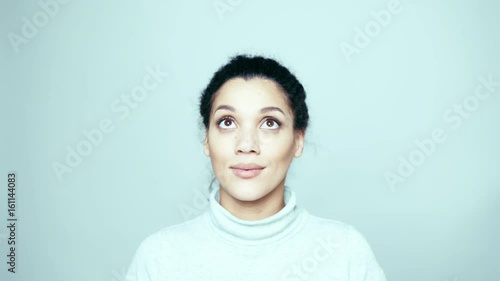 Closeup of young mixed race African American - Caucasian woman looking left, up and right at blank copy space, then looking at camera smiling, locked down real time video, toned video