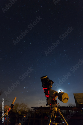 Professional astrophotography telescope equipped with guider scope and astro camera is taking pictures of night sky