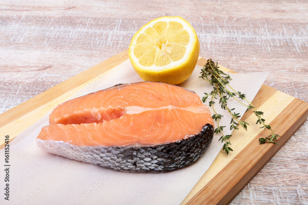 fresh raw salmon with spices and lemon on wooden cutting board. ready for cookin fresh raw salmon with spices and lemon on wooden cutting board. ready for cookin