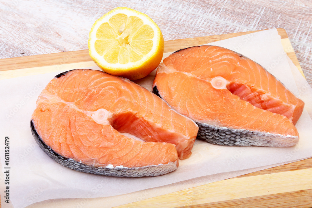 fresh raw salmon with spices and lemon on wooden cutting board. ready for cookin