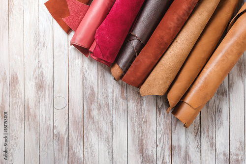 Multicolored leather in rolls on wooden background. photo