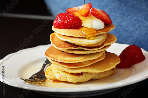Pancakes with strawberries on white plate,flowing honey, fork, healthy lifestyle, breakfast