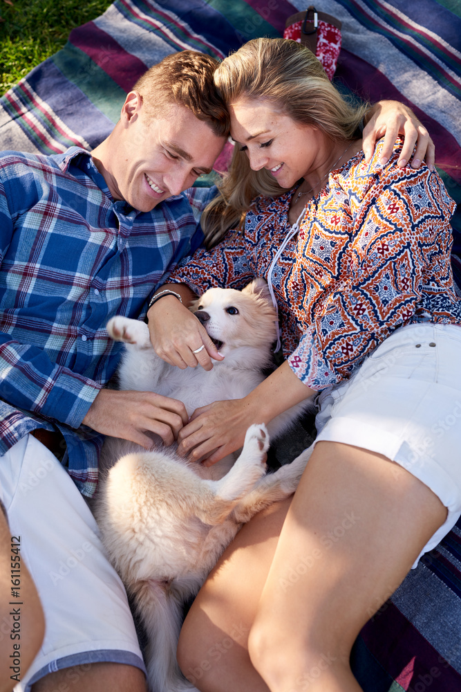 Young couple on blanket with puppy Young couple on blanket with puppy