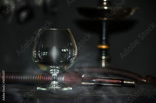 Heavy hookah smoke under a brandy glass on a gray background, hookah tube photo