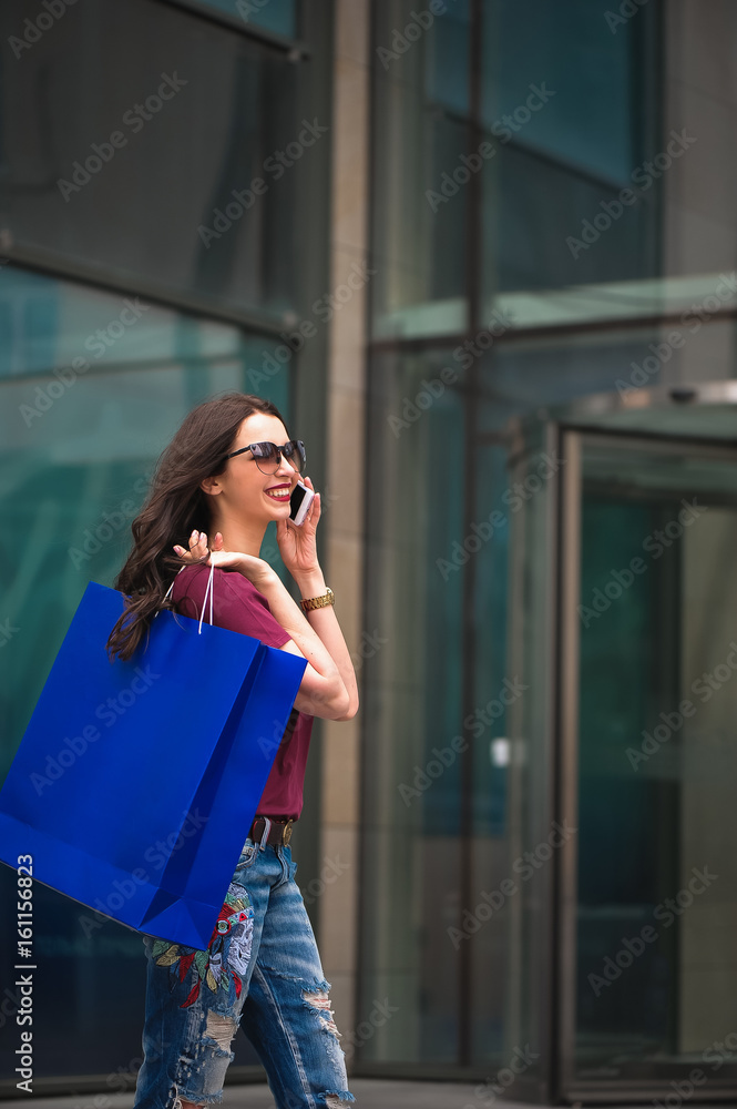 Beautiful girl with shopping bags going to the store on the street