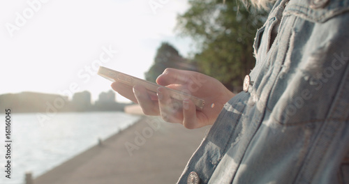 Close up of young female hands using phone, outdoors. © therabbithole