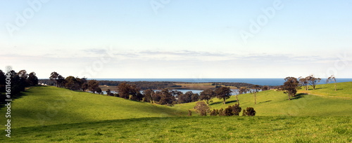 Central Tilba in its idyllic setting near Narooma. Autumn scene in rural New South Wales Australia. Farmland fields, trees, ponds and hills.