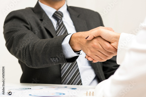 Businessman making handshake with a businesswoman in the meeting