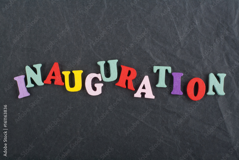Iinauguration . English word on black board background composed from colorful abc alphabet block wooden letters, copy space for ad text. Learning english concept.