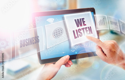 A businesswoman selecting a We Listen business concept on a futuristic portable computer screen.