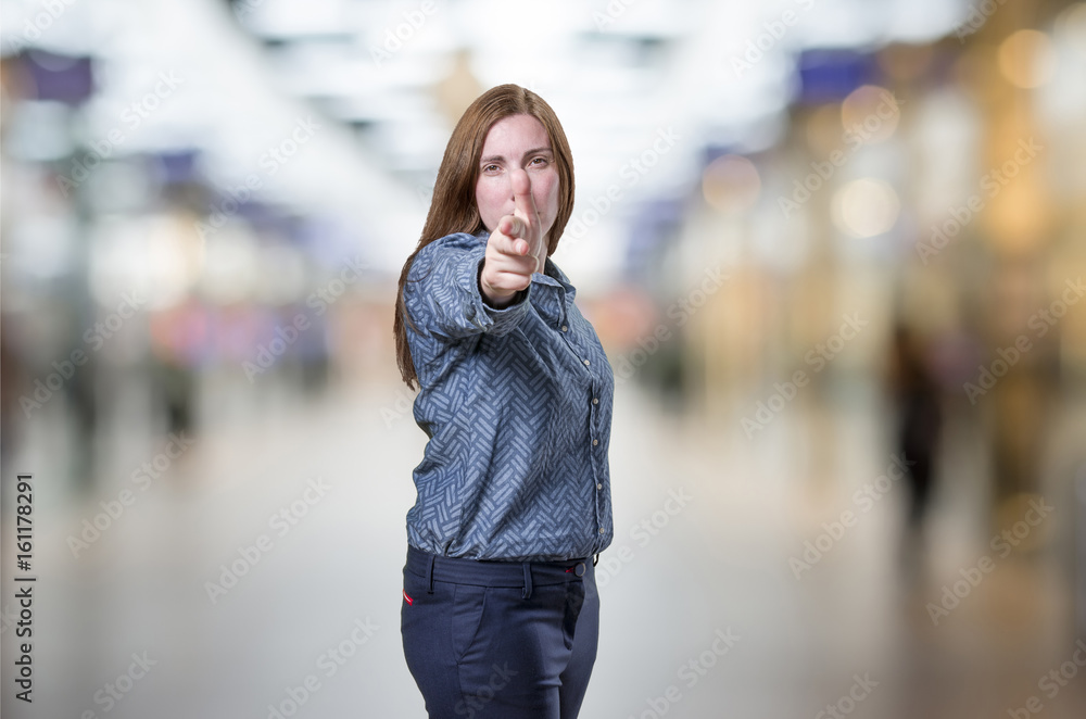Pretty business woman making gun gesture over blur background