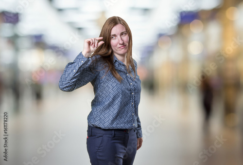 Pretty business woman doing tiny sign over blur background