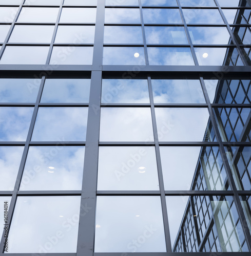reflections of blue sky and clouds in glass facade of modern office building