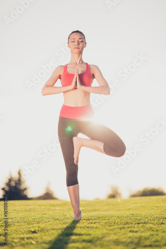 Young sport woman meditates while practicing yoga in a spring morning park. Freedom, calmness, harmony and relax, women happiness