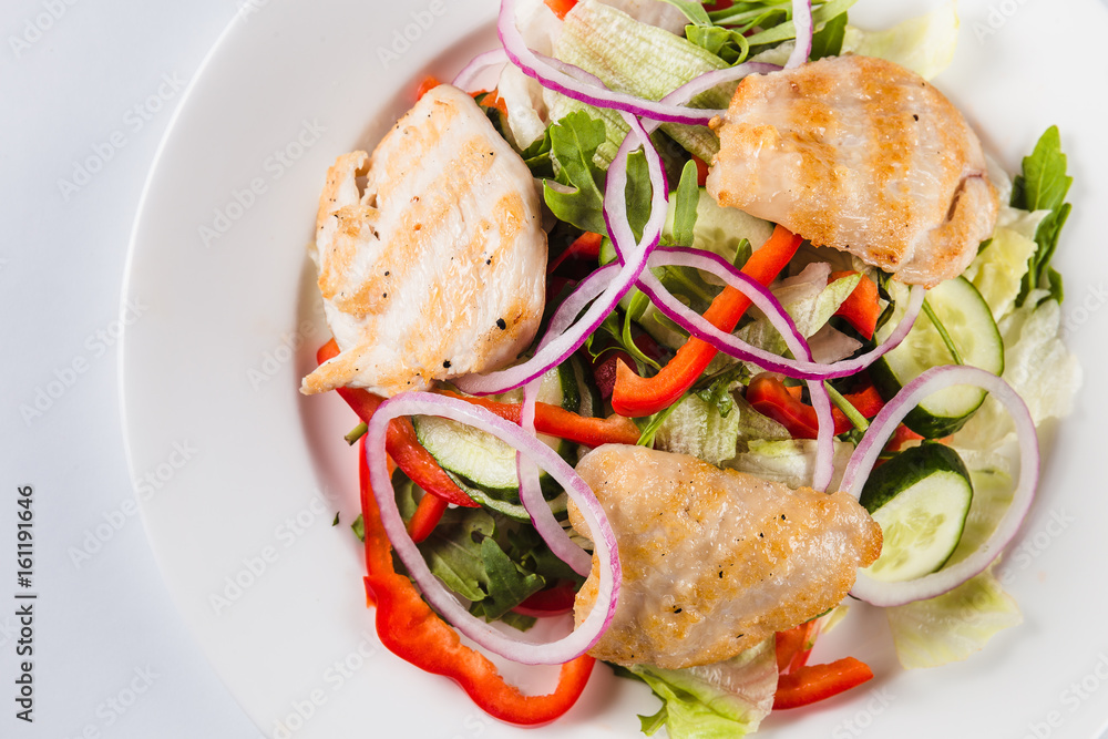 salad with chicken on a white plate on a light background (top view close)