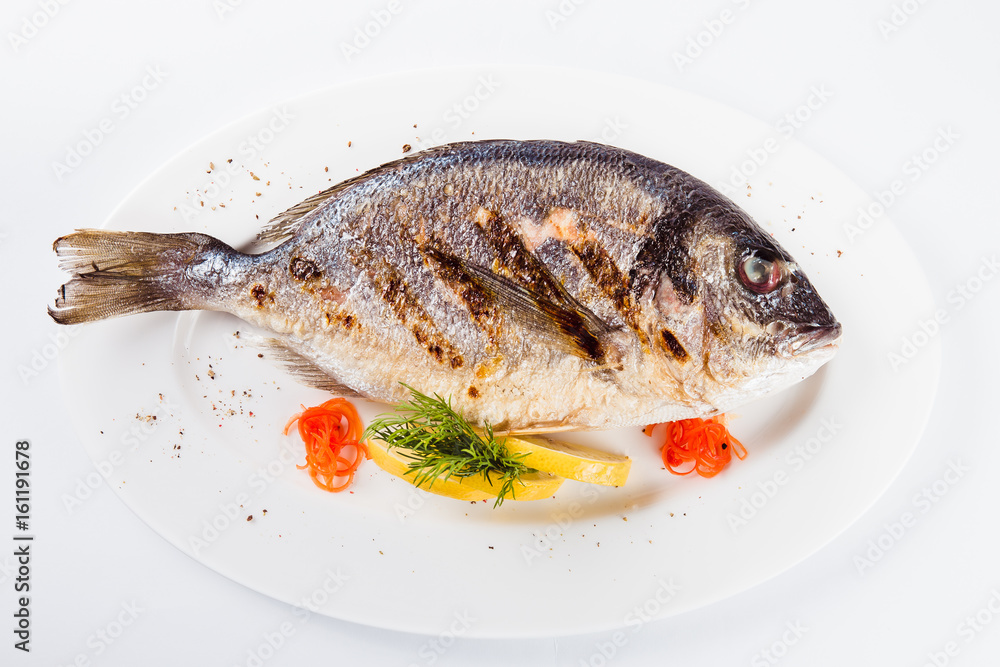 grilled dorada on a white plate on a light background (top view close) grilled dorada on a white plate on a light background (top view close)