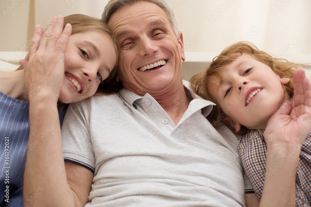 Loving positive gentleman hugging his grandchildren Loving positive gentleman hugging his grandchildren