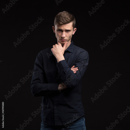 Young man portrait of a confident businessmanon black background. Ideal for banners, registration forms, presentation, landings, presenting concept.