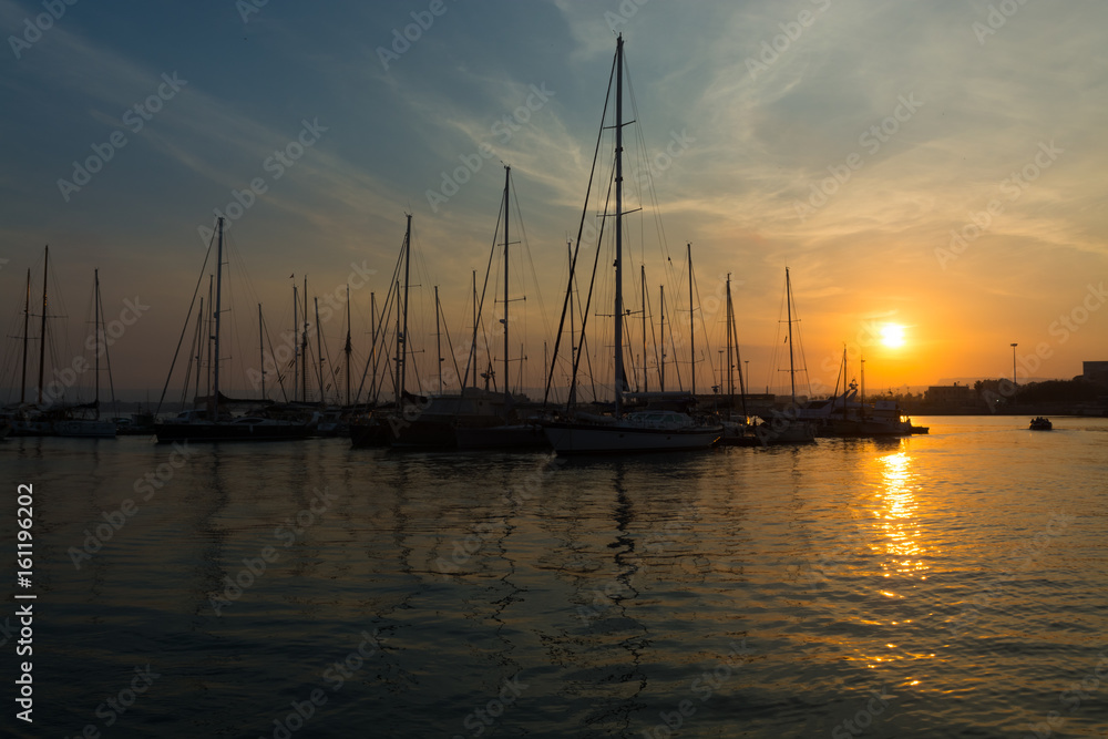 Beautiful port for luxury yachts in the rays of the setting summer sun. Sunset at the port for yachts. Yacht club in Italy, Ortigia, Siracusa