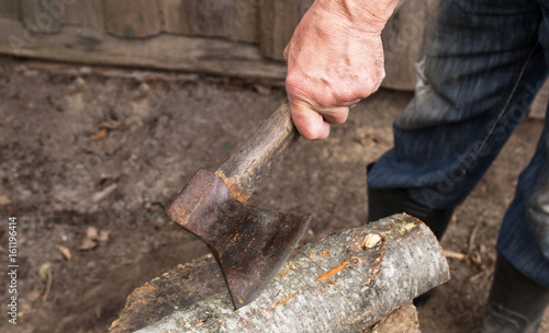 Worker, an elderly man with an old axe chops firewood. Forced to work in retirement . Employee .