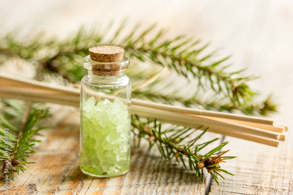Bottles of sea salt and fir branches for aromatherapy and spa on wooden table background Bottles of sea salt and fir branches for aromatherapy and spa on wooden table background