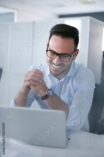 Business man sitting in office and waiting e mail in laptop. Business man watching something on computer.