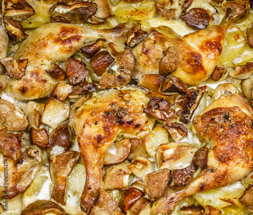 Baked chicken drumsticks with potatoes and mushrooms closeup